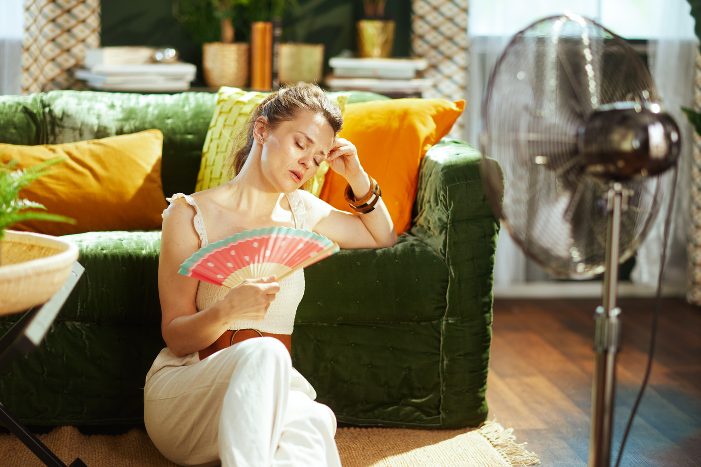 Woman Uses Hand Fan and Electric Fan for Heat